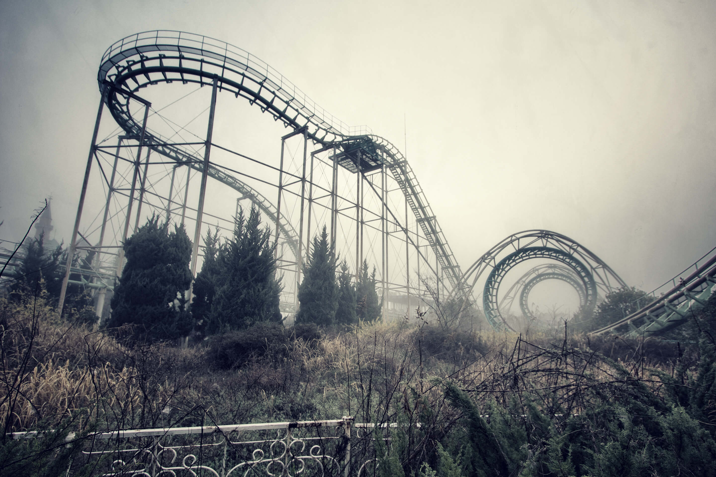 Misty morning view of the abandoned Screwcoaster roller coaster at the overgrown Nara Dreamland in Japan.