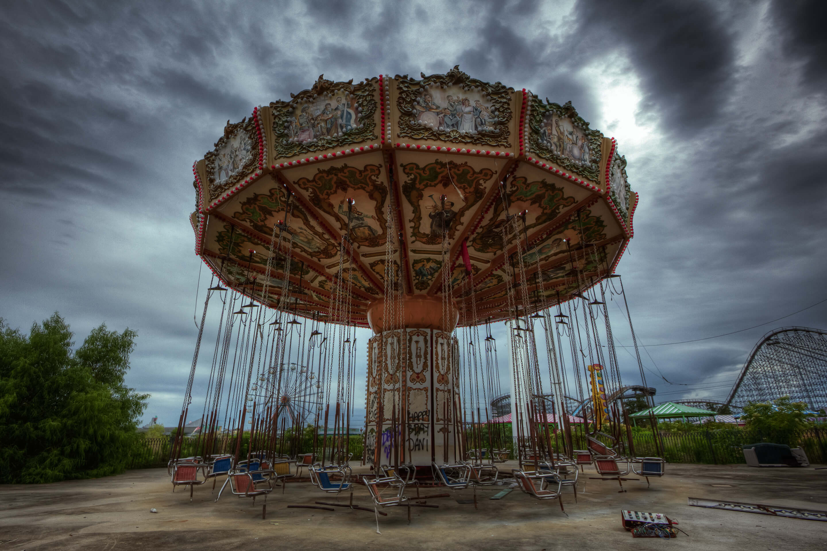 Abandoned wave swinger ride at the derelict Six Flags New Orleans amusement park under stormy skies.
