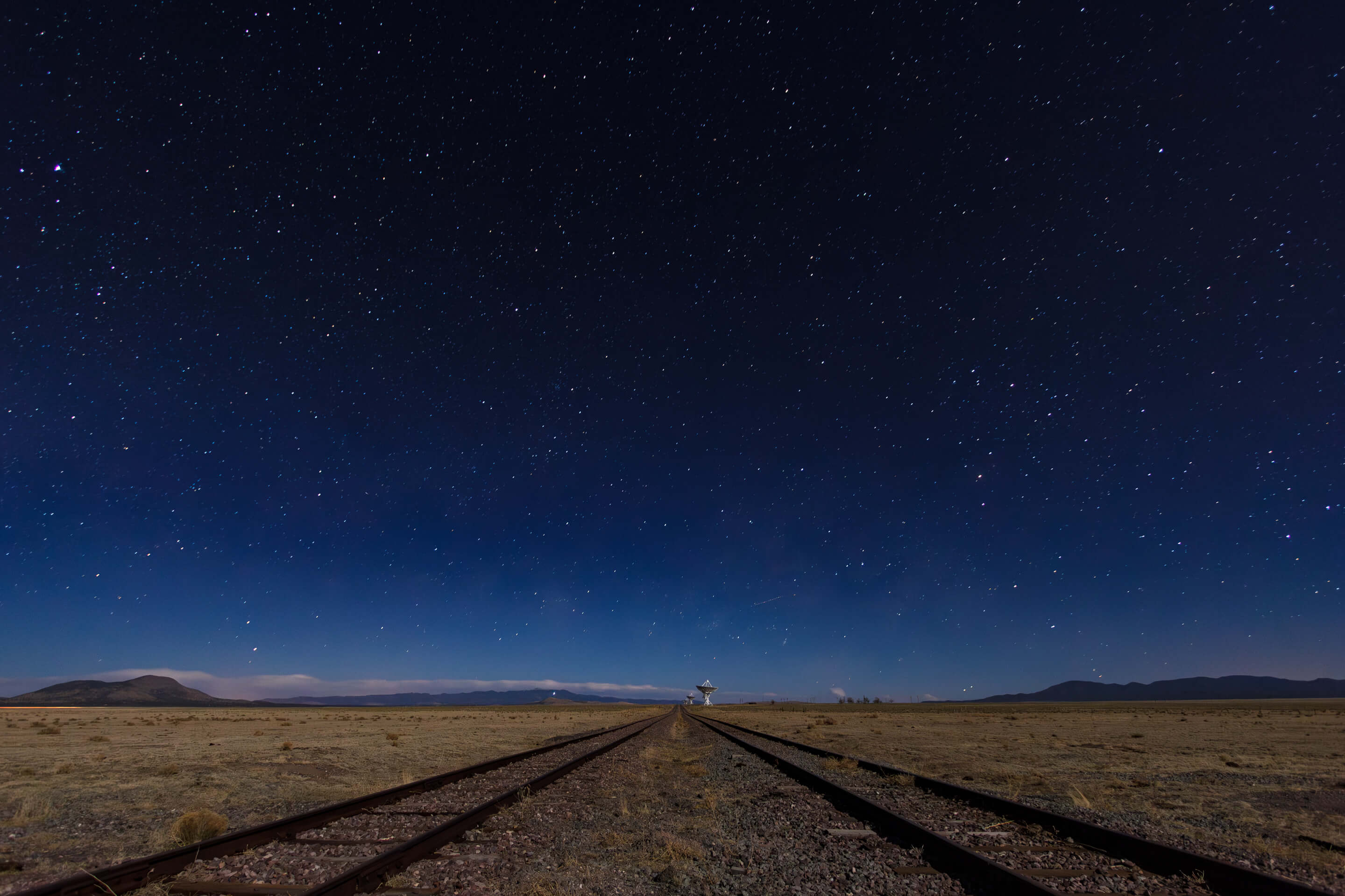 Long-exposure night sky over railway tracks leading toward the Very Large Array in New Mexico.